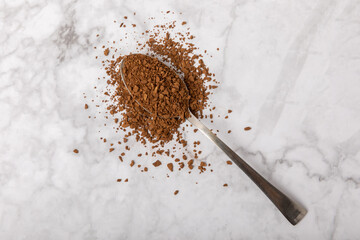 Instant coffee in a spoon. Coffee in granules on a white marble background.Energy hot drink. Place...