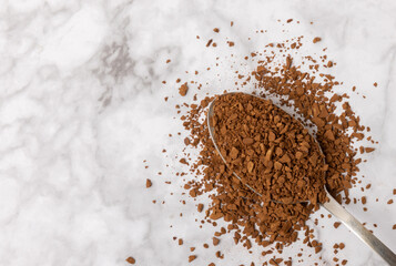 Instant coffee in a spoon. Coffee in granules on a white marble background.Energy hot drink. Place...