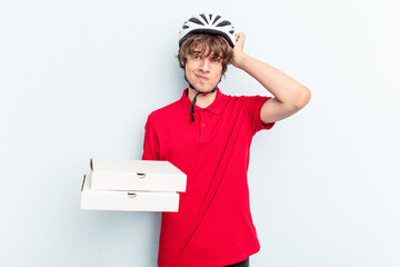 Young delivery caucasian man holding pizzas isolated on blue background being shocked, she has remembered important meeting.