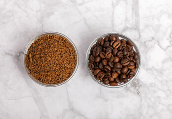 Coffee granules and coffee beans on a white marble background. Instant coffee drink. Energy hot...
