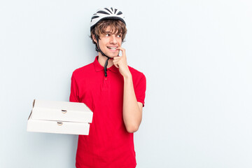 Young delivery caucasian man holding pizzas isolated on blue background relaxed thinking about something looking at a copy space.