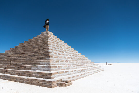 Woman standing on top of a lonely pyramid in Uyuni