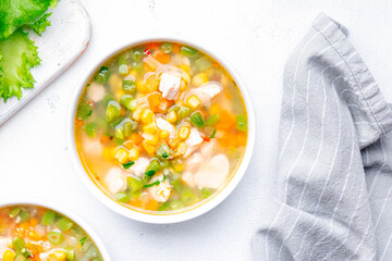 Light vegetable soup with chicken, corn and green beans. Comfort food. White table background, top view