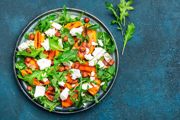 Delicious grilled peach salad  with cheese, hazelnuts and arugula on blue background, top view