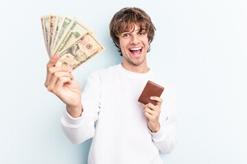 Young caucasian man holding wallet and banknotes isolated on blue background