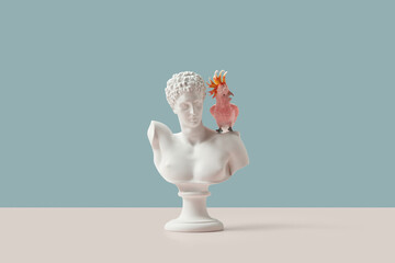 White Roman bust with pink toy parrot.