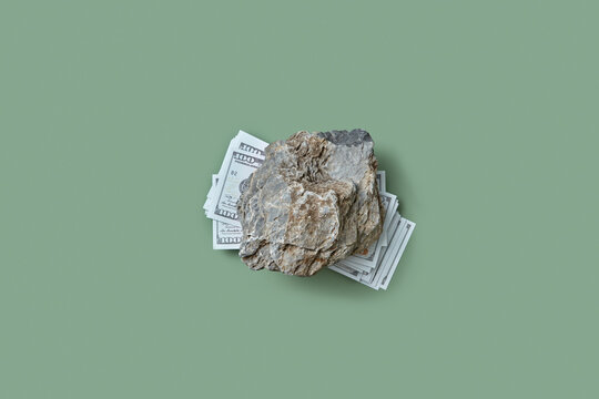 100 dollar banknotes crushed by gray stone.
