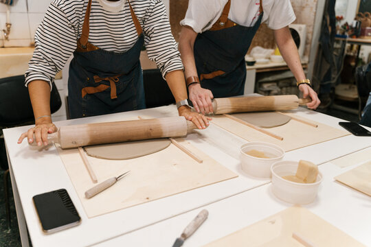 Anonymous potters rolling clay pieces in workshop
