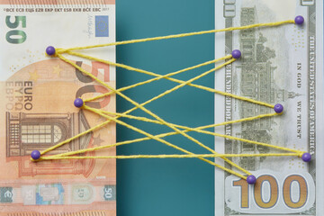 Euro and dollar pinned with intertwined threads.