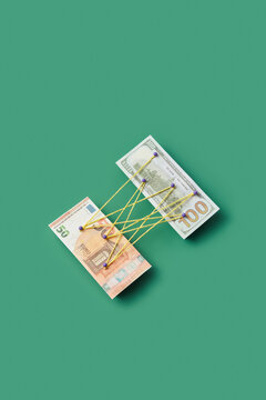 Dollar and euro pinned with tangled threads.