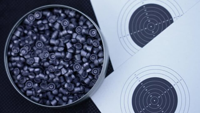 paper with shooting targets and a box full of gun pellets next to it. High quality 4k footage
