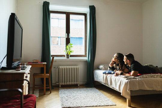 Couple laying on bed looking at the window
