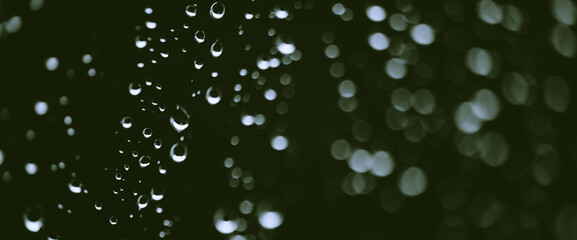 Atmospheric minimal monochrome backdrop with rain droplets on glass. Wet window with rainy drops and dirt spots closeup. Blurry minimalist background of dirty window glass with raindrops close up.