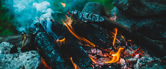 Vivid smoldered firewoods burned in fire close-up. Atmospheric warm background with orange flame of...