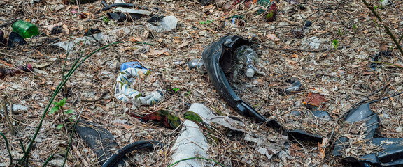 Garbage pile in forest among plants. Toxic plastic into nature everywhere. Rubbish heap in park...