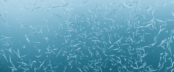 Minimal light backdrop with icy crystals on window in day light. Frosty texture on glass closeup in blue light. Blurry minimalist monochrome background of icy pattern on frozen window glass close up.