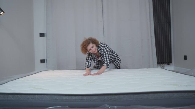 Senior woman feeling happy about her new comfortable mattress at home. Concept of healthy sleep. Comfortable sleep. An elderly woman is happy with a new mattress in a new rented apartment.