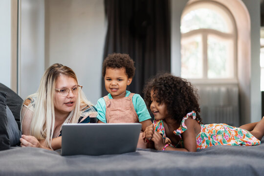 Mother And Kids Talking While Using Laptop In The Bedroom
