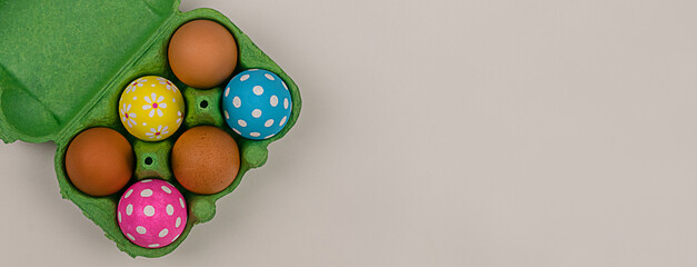 Easter eggs in carton box on grey background. Top view with copy space flat lay