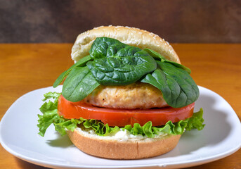 salmon burger top  with spinach  on a sesame bun