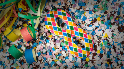 Fototapeta na wymiar Carnival themed background with Harlequin mask over confetti, buglers and streamers