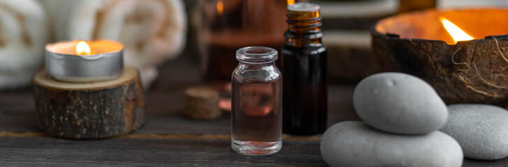 Concept of natural essential organic oils, Bali spa, beauty treatment, relax time. Atmosphere of relaxation, pleasure. Candles, towels, dark wooden background. Alternative oriental medicine. Banner