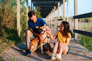 Happy couple caressing dog in park