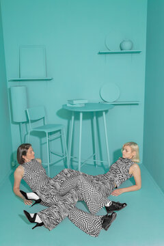 conceptual portrait of two girls in an art space with intertwined legs