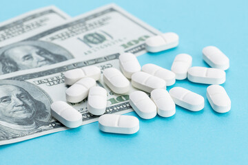 Medicine cost concept. US Dollars bills and medicine pills on blue background