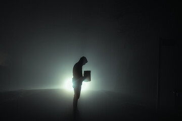 A man silhouetted against car headlights at night
