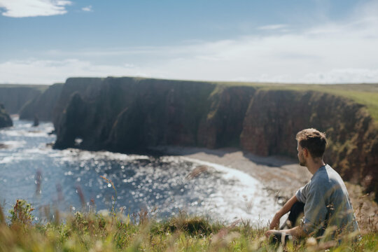 Man relaxing at Sea Stacks At Duncansby Head. Highlands, Scotland