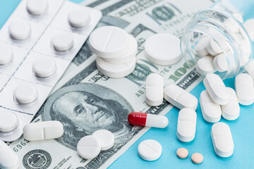 High cost of Medicine concept. US Dollars bills and medicine pills on blue background