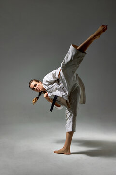 Woman in Karate uniform kicking air