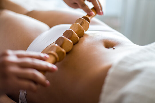 Masseuse massaging belly with wooden roller
