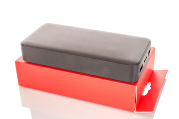 One black portable power bank charger with red paper box, close-up isolated on white background.