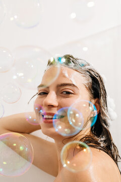Portrait of a young woman in the shower with soap bubbles
