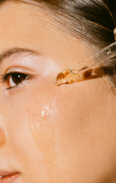 A young woman applying a face and body oil 