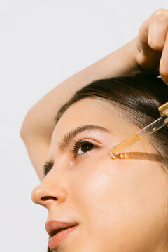 A young woman applying a face and body oil 
