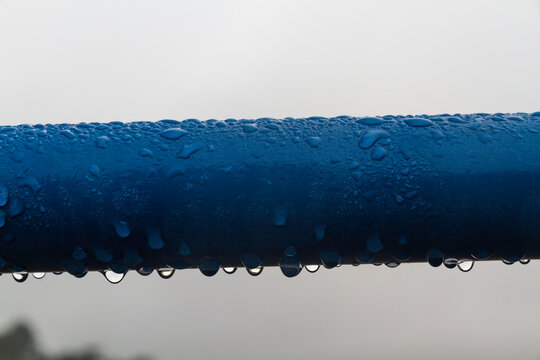 Close Up Of Water Rain Drops On Blue Pipe.