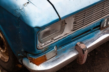 Close-up headlight of an old car and a repaired auto fender. Headlight of an old rusty car close up