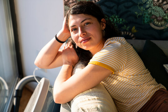 Beautiful brunette leaning on a couch by window 