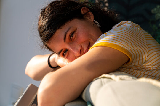 Beautiful brunette leaning on a couch by window 