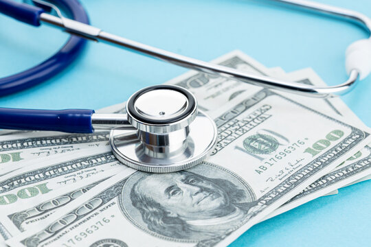 Health care cost concept. US Dollars bills and stethoscope on blue background