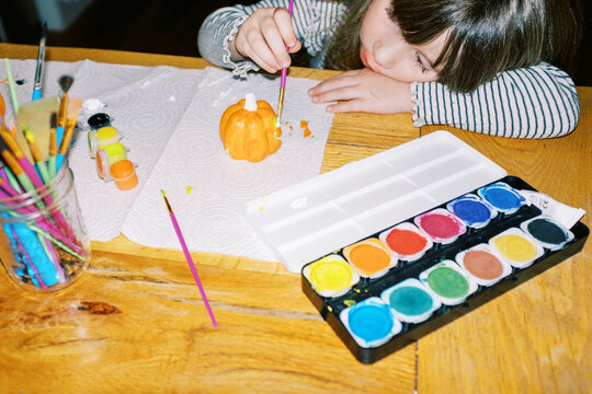 Little toddler girl painting porcelain pumpkins