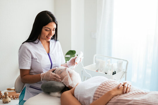 Beautician performing darsonvalization in salon