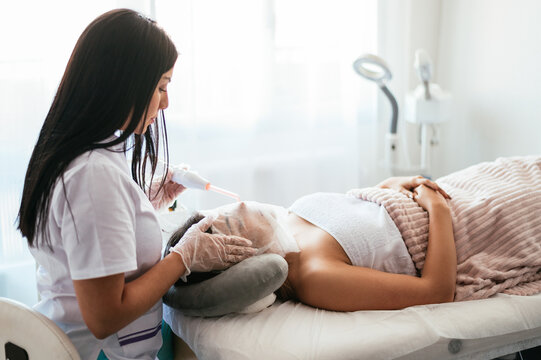 Beautician performing darsonvalization in salon