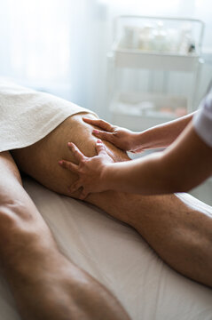 Crop masseuse massaging leg of client