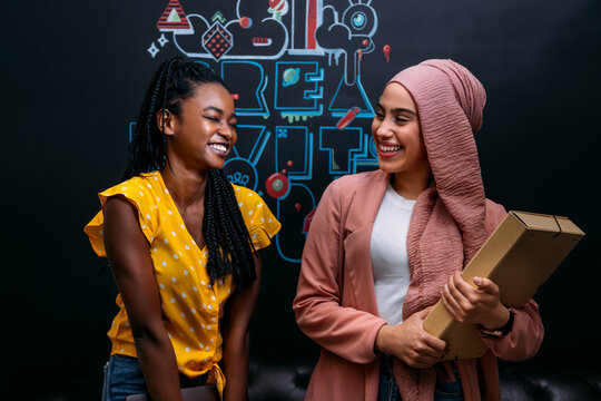 Smiling multiethnic women with folders in creative office