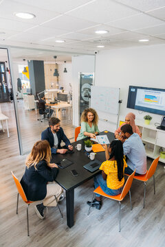 Unrecognizable diverse partners speaking at office desk