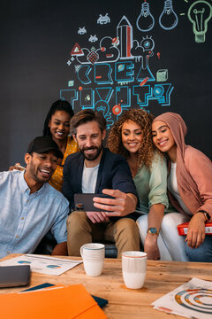Cheerful multi coworkers taking selfie on smartphone in office